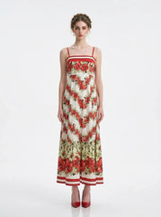 Woman wearing a floral print maxi dress with spaghetti straps, standing against a white background.