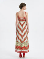 Back view of a woman in a floral print maxi dress with spaghetti straps, standing against a white background.