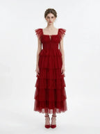 Woman in a red tiered tulle dress with ruffled sleeves and a square neckline, front view