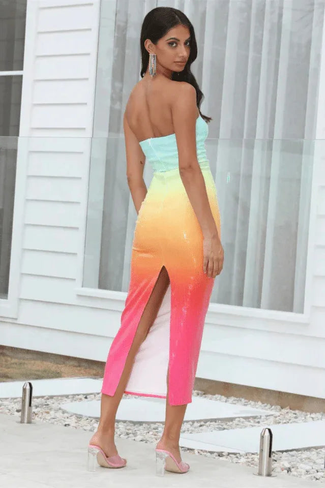 Back view of a woman in a strapless ombre sequin midi dress with a thigh-high slit, outdoors. Secondary image