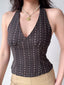 Woman wearing a dark brown halter top with a small floral print and a gold pendant necklace.