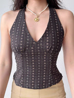 Close-up of a woman's torso wearing a dark brown halter top with a small floral print.