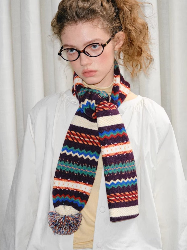 Close-up of a model wearing a white jacket and a multicolor knit scarf.