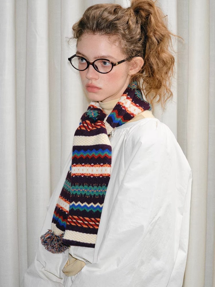 Model looking to the side, wearing a white jacket and a patterned knit scarf.