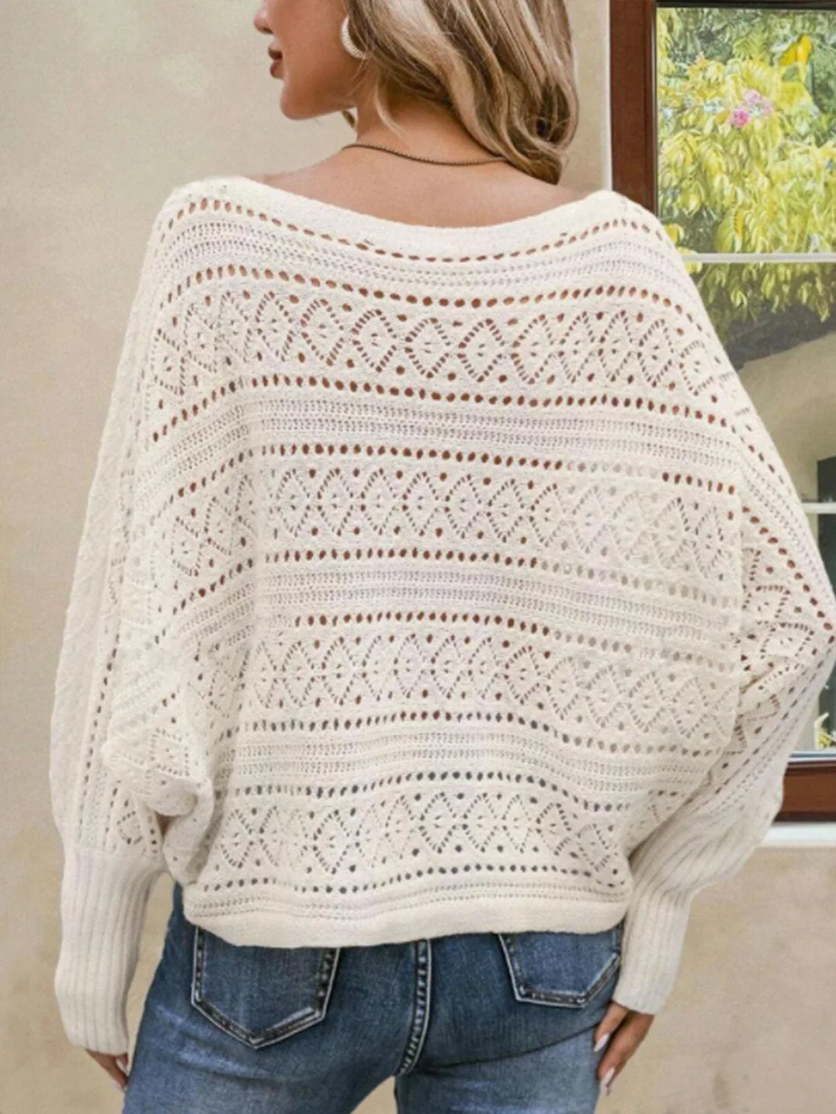 Back view of a white open-knit sweater with bell sleeves and a relaxed fit.