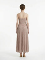 Back view of a woman in a strapless, metallic knit maxi dress with a self-tie belt.