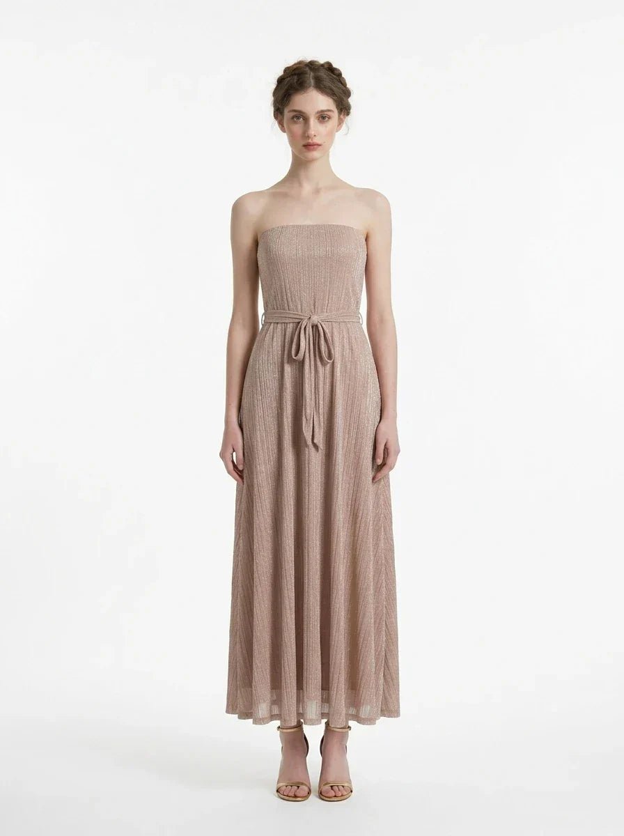 Woman wearing a strapless, metallic knit maxi dress with a self-tie belt, standing against a white background.