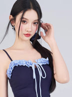 Close-up of the ruffled neckline and drawstring detail on the navy swimsuit.