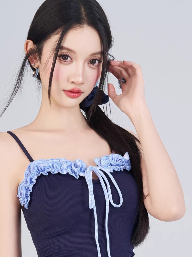 Close-up of the ruffled neckline and drawstring detail on the navy swimsuit.