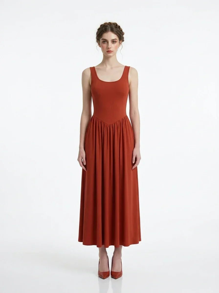 woman wearing a rust-colored ribbed knit midi dress with a scoop neckline and sleeveless design, standing against a white background