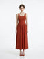 woman wearing a rust-colored ribbed knit midi dress with a scoop neckline and sleeveless design, standing against a white background