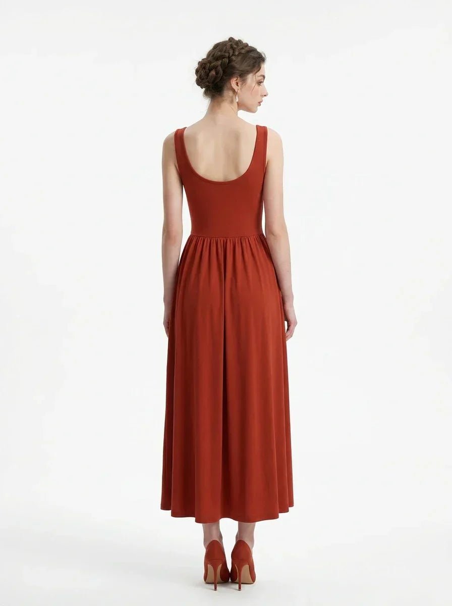 back view of a woman wearing a rust-colored ribbed knit midi dress with a scoop neckline and sleeveless design, standing against a white background