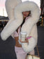 Woman wearing a white faux fur cropped jacket with an oversized hood and pink lounge pants, holding a coffee cup.