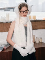 Close-up of a model wearing white fuzzy accessories, including earmuffs, a scarf, and gloves.
