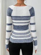 Back view of a woman wearing a blue and white striped fuzzy knit sweater with a square neckline and black pants.