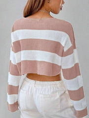 Back view of a woman wearing a pink and white striped cropped sweater with a v-neck and long sleeves, paired with white pants.