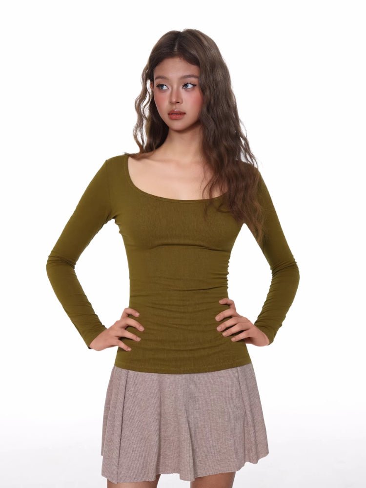 Model wearing a fitted, olive green, long-sleeved, scoop neck top with a ribbed texture and ruched side detail.