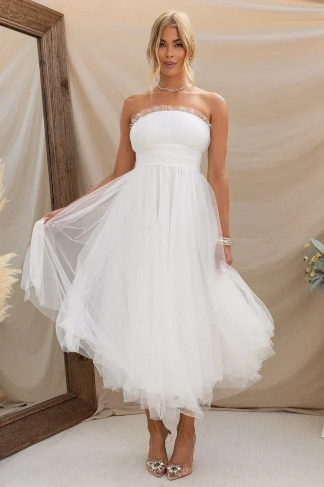 Woman twirling in a white strapless tulle midi dress, showcasing the flowy skirt. Secondary image