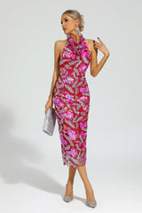 Woman wearing a red sequined halter midi dress with floral appliques, holding a silver clutch.