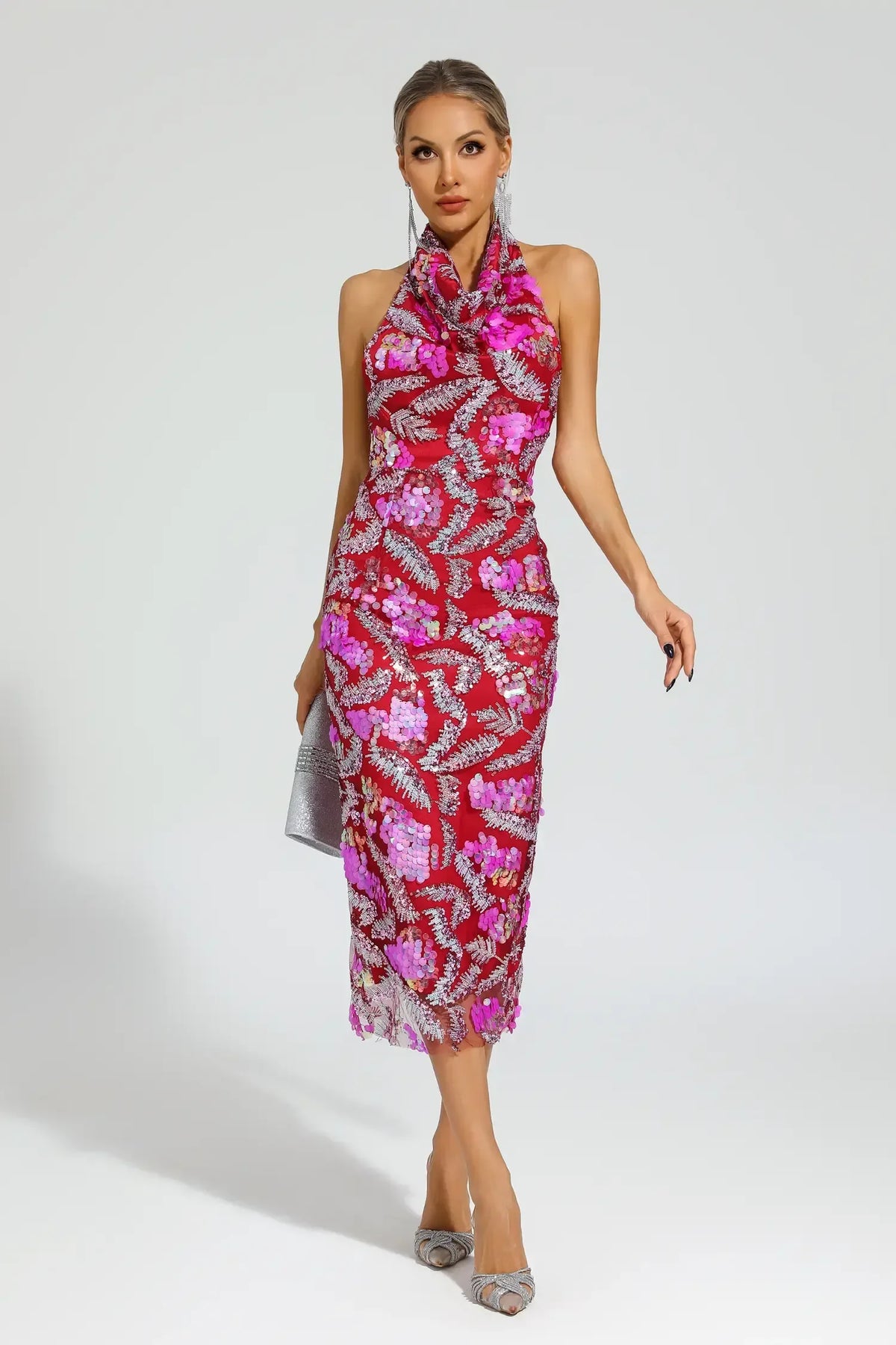 Woman in a red sequined halter midi dress with floral appliques, walking.