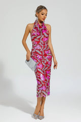 Woman in a red sequined halter midi dress with floral appliques, holding a silver clutch and posing.